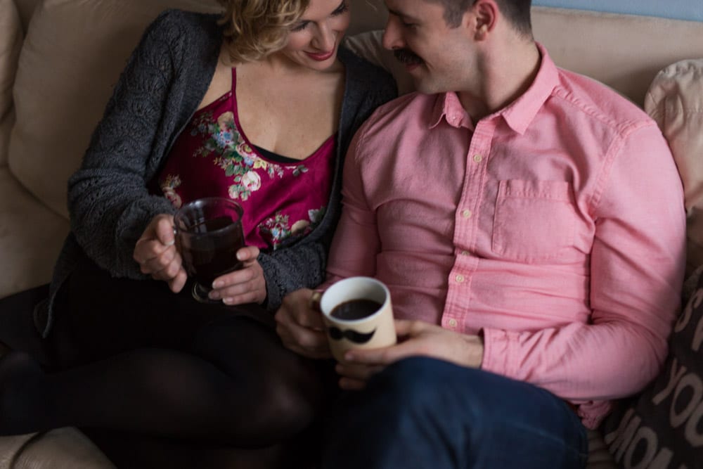 couple drinks coffee on couch in holiday attire