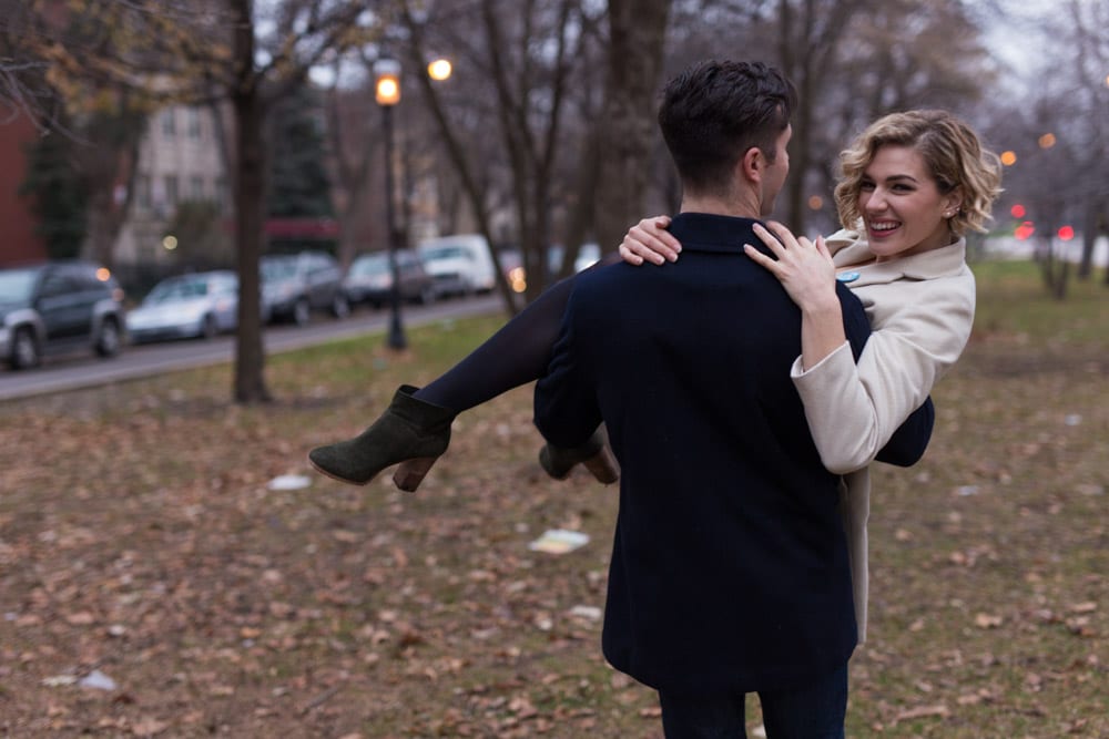 man carries woman through boulevard