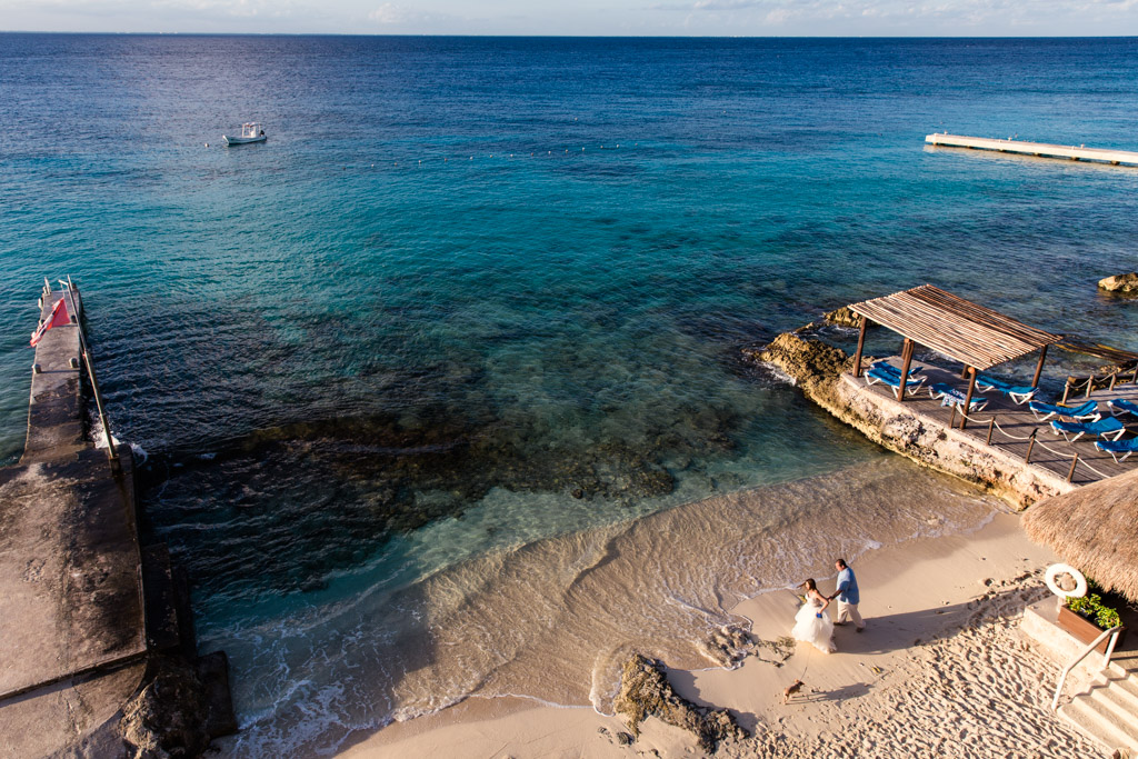 Bride and groom walk barefoot on beach at their destination wedding in Cozumel, Mexico