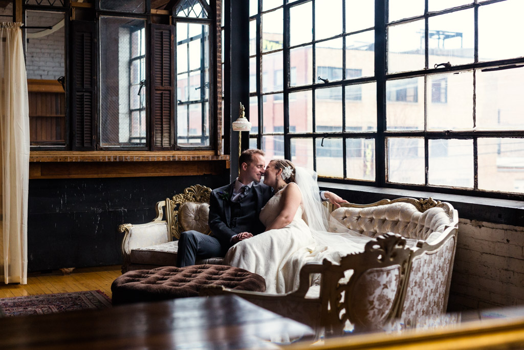 Bride and groom enjoy a newlywed moment on vintage couch at Chicago Salvage One wedding