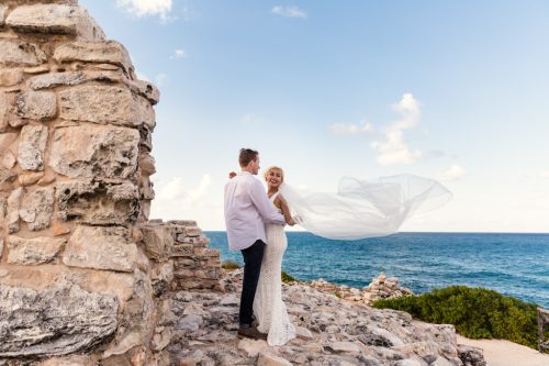 Bride and groom at Mayan Temple with veil flying in wind at their Isla Mujeres destination wedding