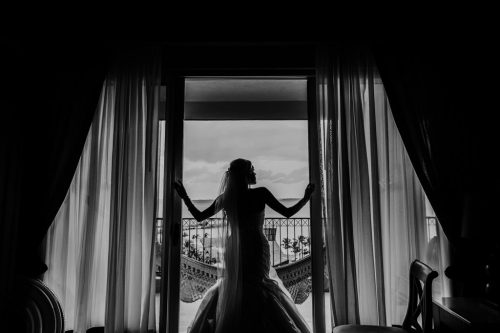 Bride looks out hotel room window in Mexico at Cancun destination wedding