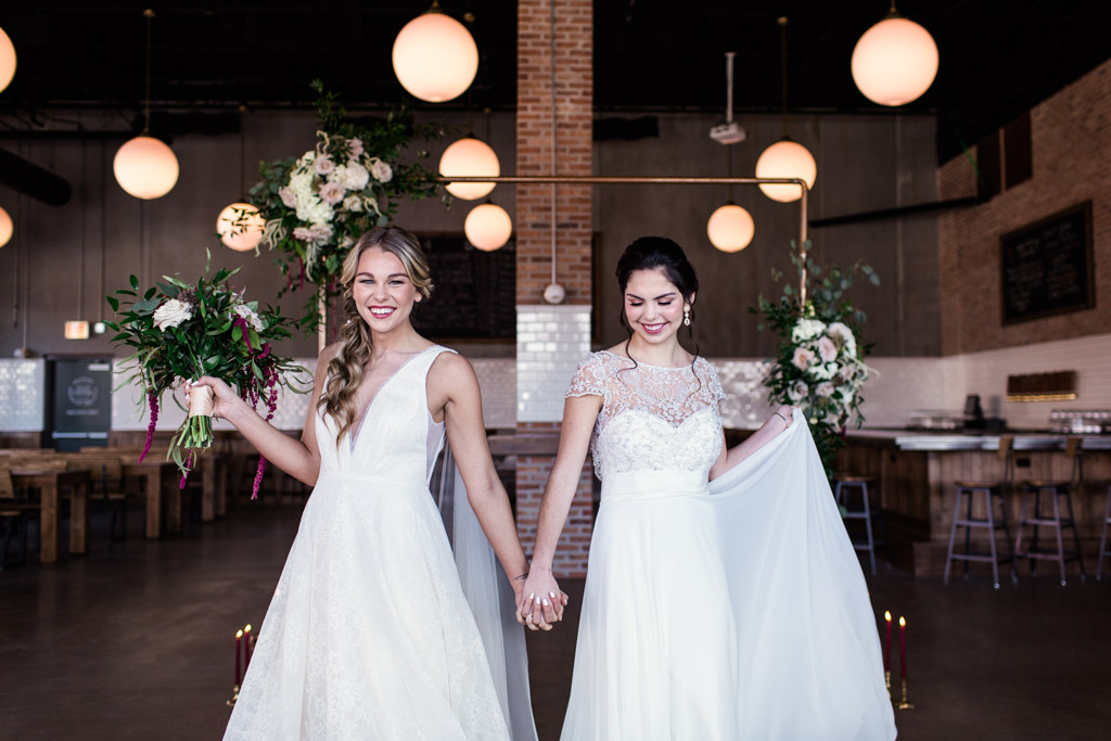 Fun photo of two brides holding hands at Great Central Brewing Company wedding styled shoot