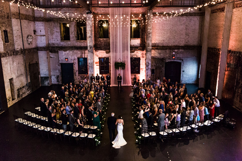 View from balcony of bride walking down the aisle at ARIA Minneapolis wedding ceremony