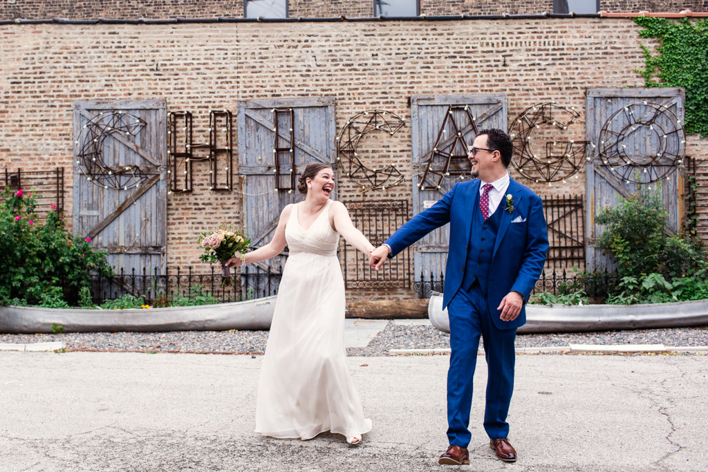 Happy bride and groom dance in courtyard of Salvage One wedding venue with CHICAGO sign