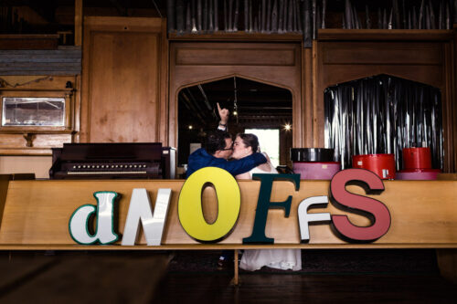 Bride and groom kiss with marquee letters at their quirky Salvage One wedding in Chicago