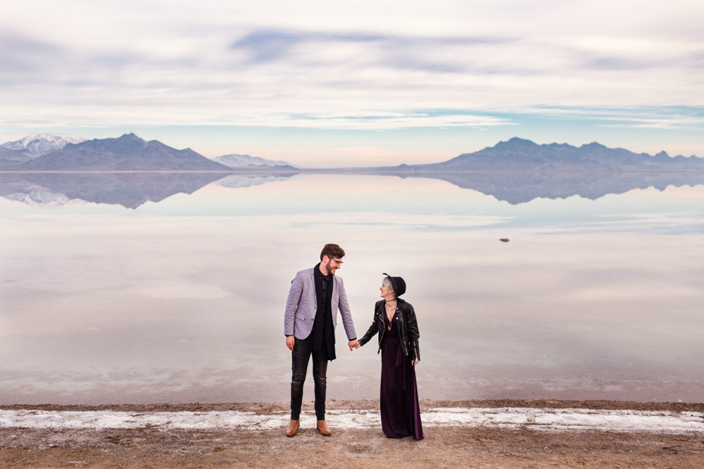 Couple holds hands at their sunrise Utah Salt Flats engagement session