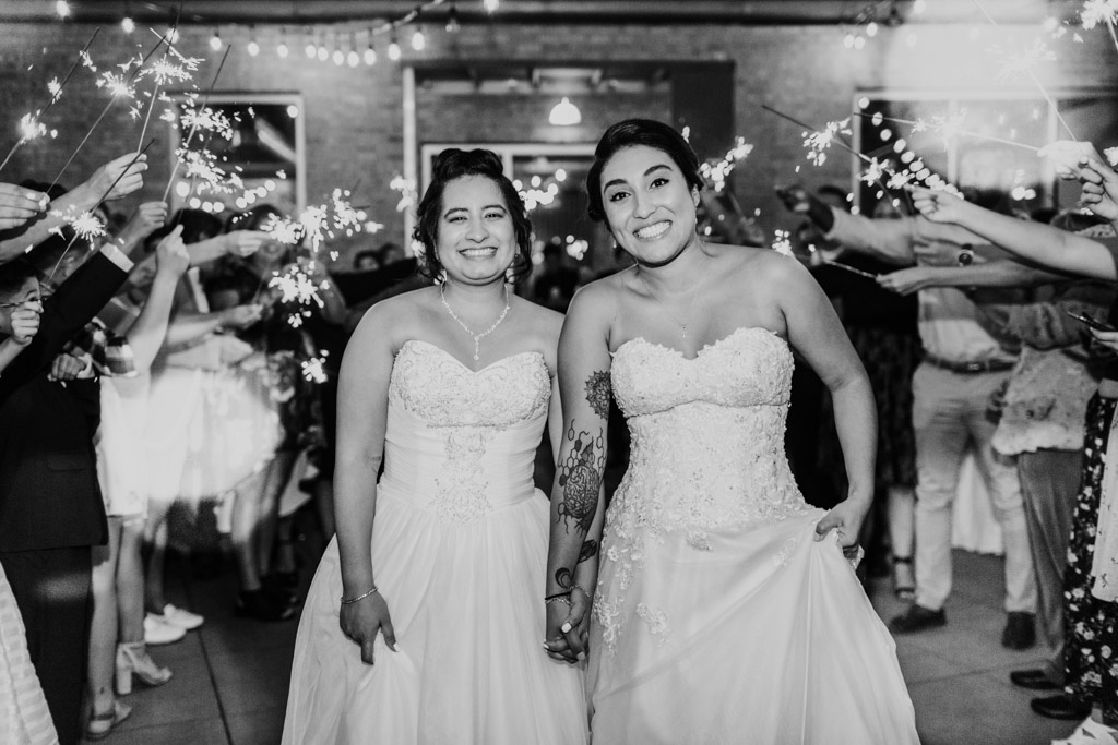 Happy brides smile during sparkler exit at their summer Concord Fifty Five wedding