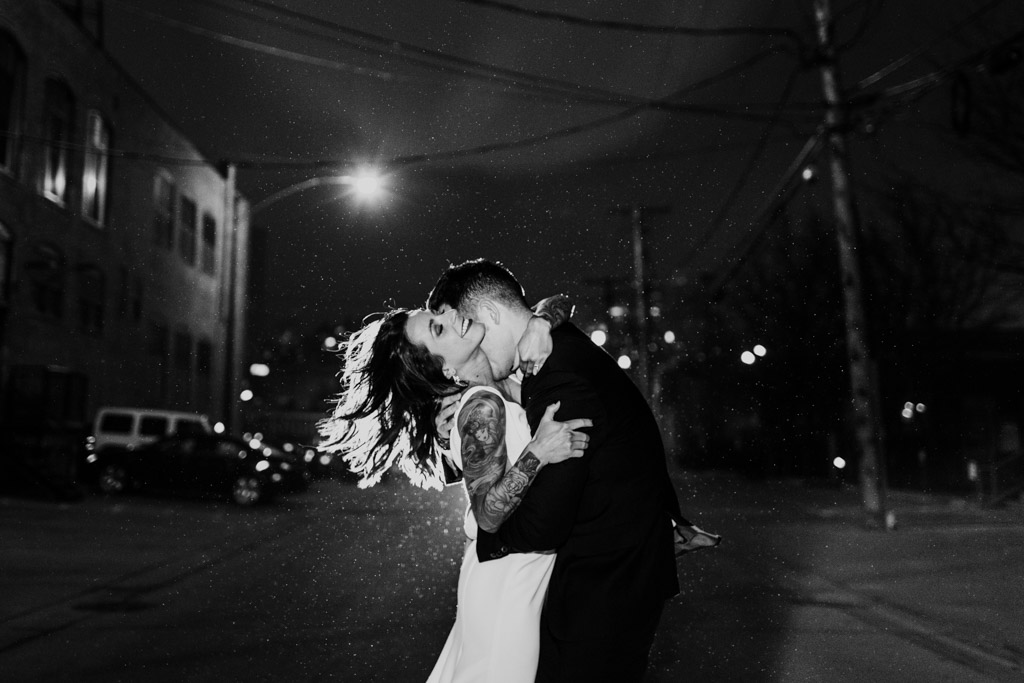 Romantic photo of bride and groom kissing with snowfall at their winter Gallery 1028 wedding