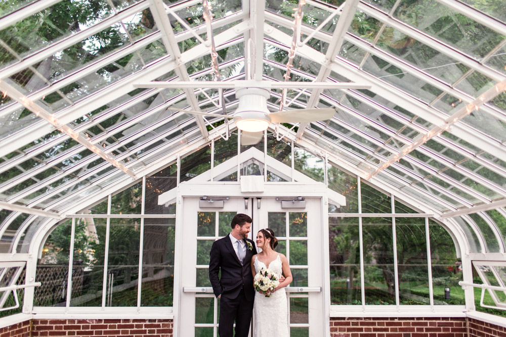 Bride and groom in greenhouse at their June Cheney Mansion wedding