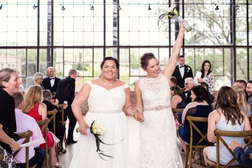 Happy brides walk down the aisle after Ravenswood Event Center wedding ceremony