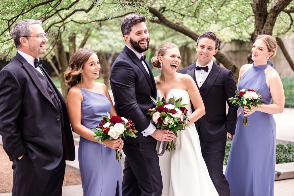 Candid photo of bride and groom laughing with wedding party at Art Institute of Chicago gardens