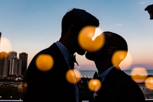 Double exposure wedding photo of two grooms kissing with sunset at Cindy's Rooftop in Chicago