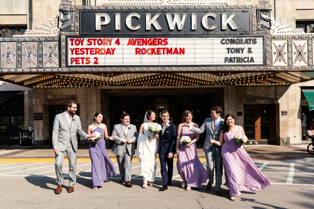 Candid Chicago wedding party photo walking in street outside historic Pickwick Theatre