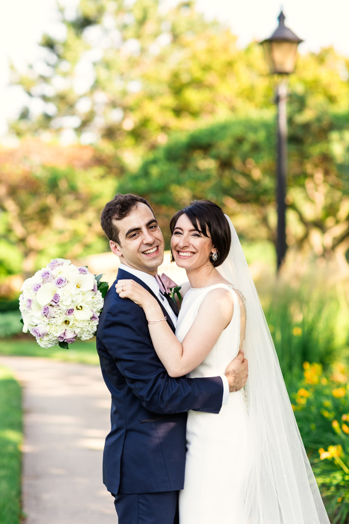 Bride and groom smile in garden before their summer wedding reception at Loews Chicago hotel