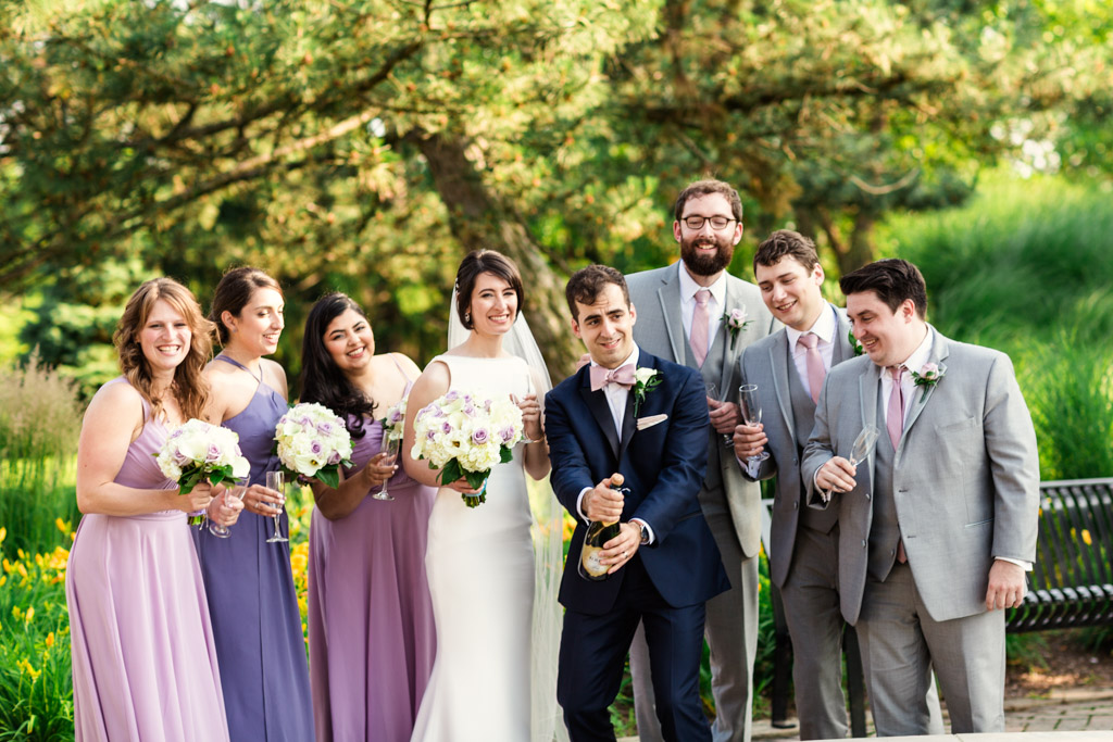 Chicago wedding party pops champagne in park before Loews Chicago wedding reception