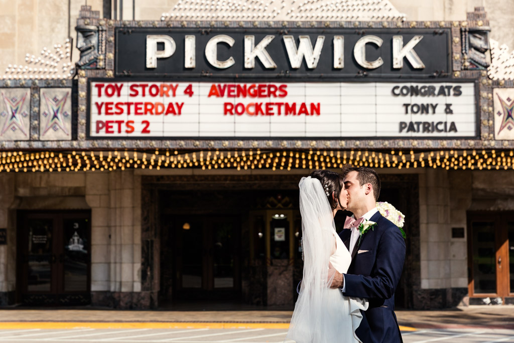 Bride and groom kiss in street outside of Pickwick movie theatre in Park Ridge, Illinois