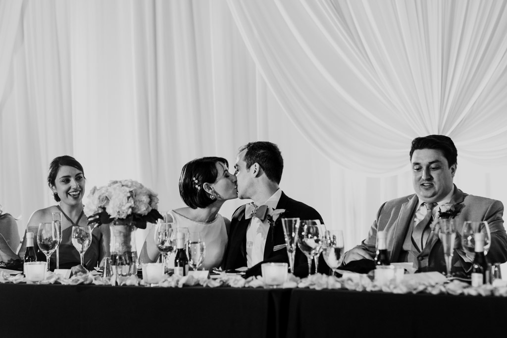 Bride and groom kiss at head table during Loews Chicago wedding reception