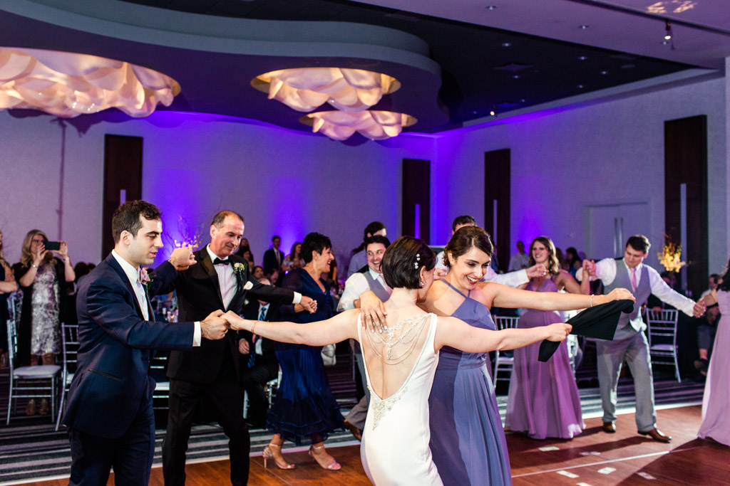 Bride and groom perform traditional Greek Orthodox dance with family at Loews Chicago wedding reception