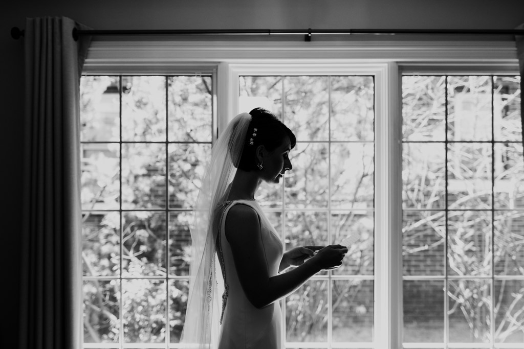 Black and white silhouette of bride reading a letter from her groom before Chicago Greek Orthodox wedding ceremony