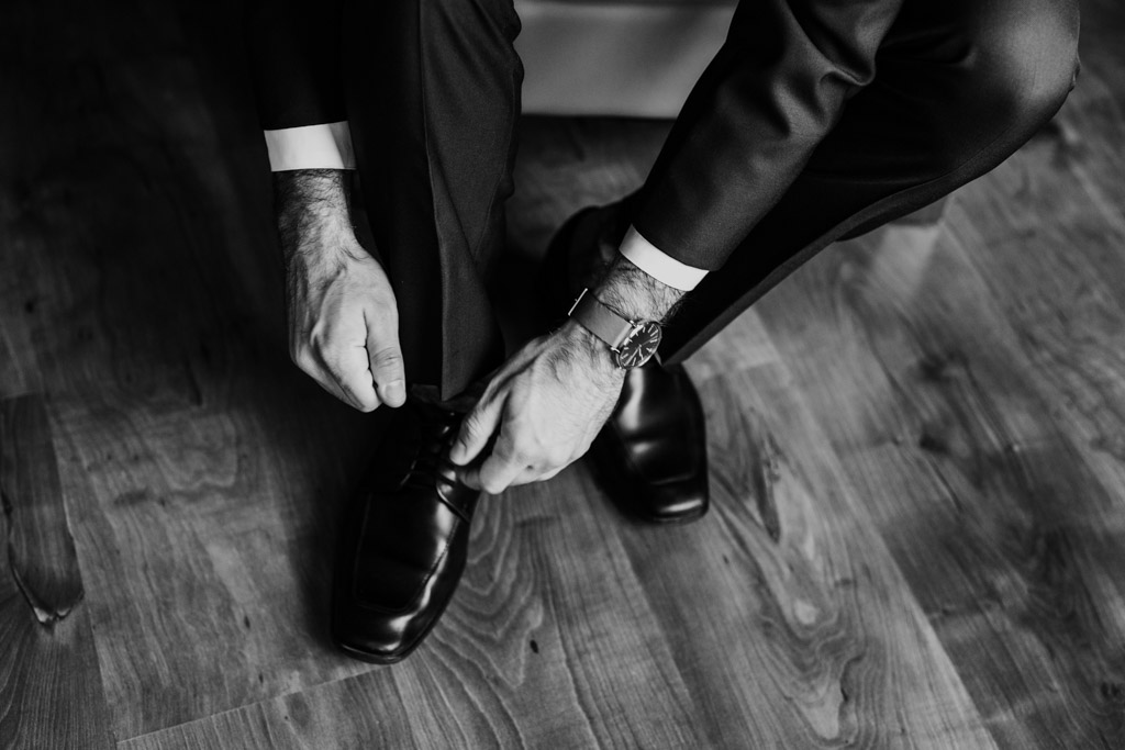 Close up photo of groom tying shoes before Chicago Greek Orthodox wedding ceremony