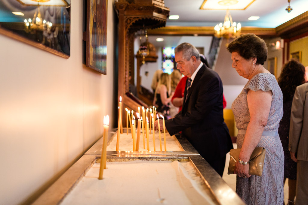 Guests light candles in sand box before Chicago Greek Orthodox wedding ceremony at St. George church