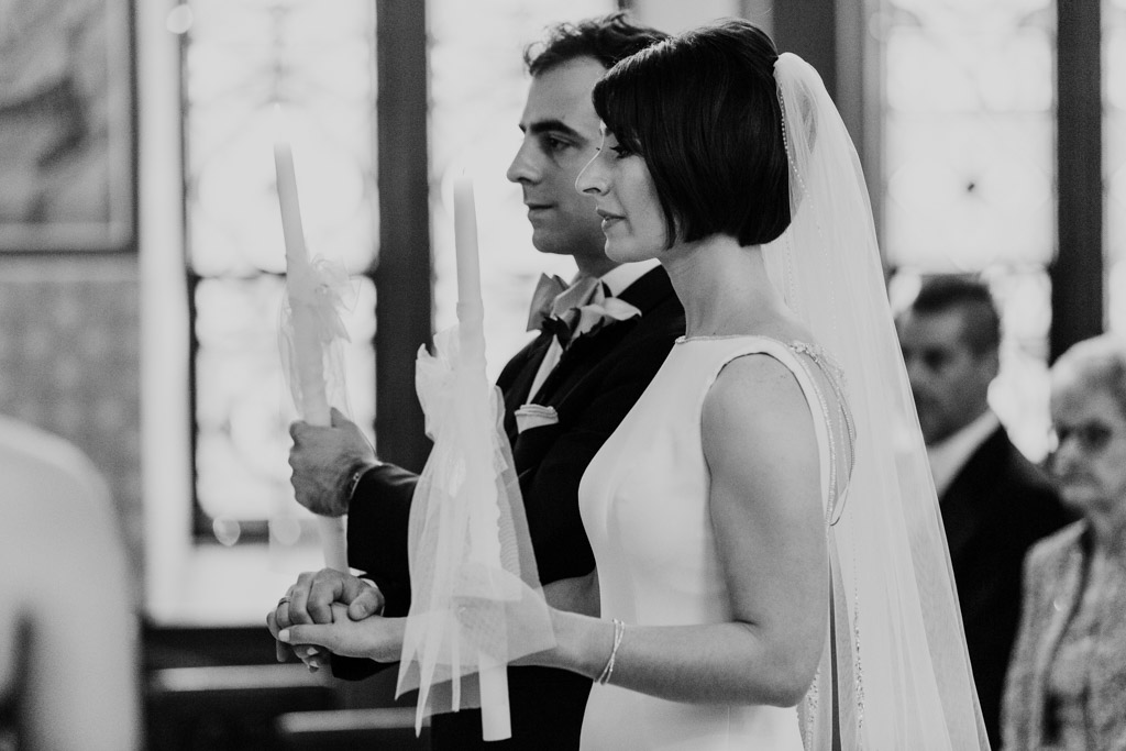 Bride and groom with candles during Chicago Greek Orthodox wedding ceremony at St. George