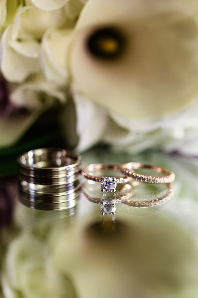 Wedding bands and engagement ring detail with spring lily bridal bouquet
