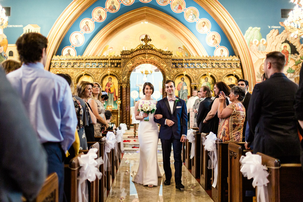 Happy bride and groom walk down aisle after their Chicago Greek Orthodox wedding ceremony at St. George