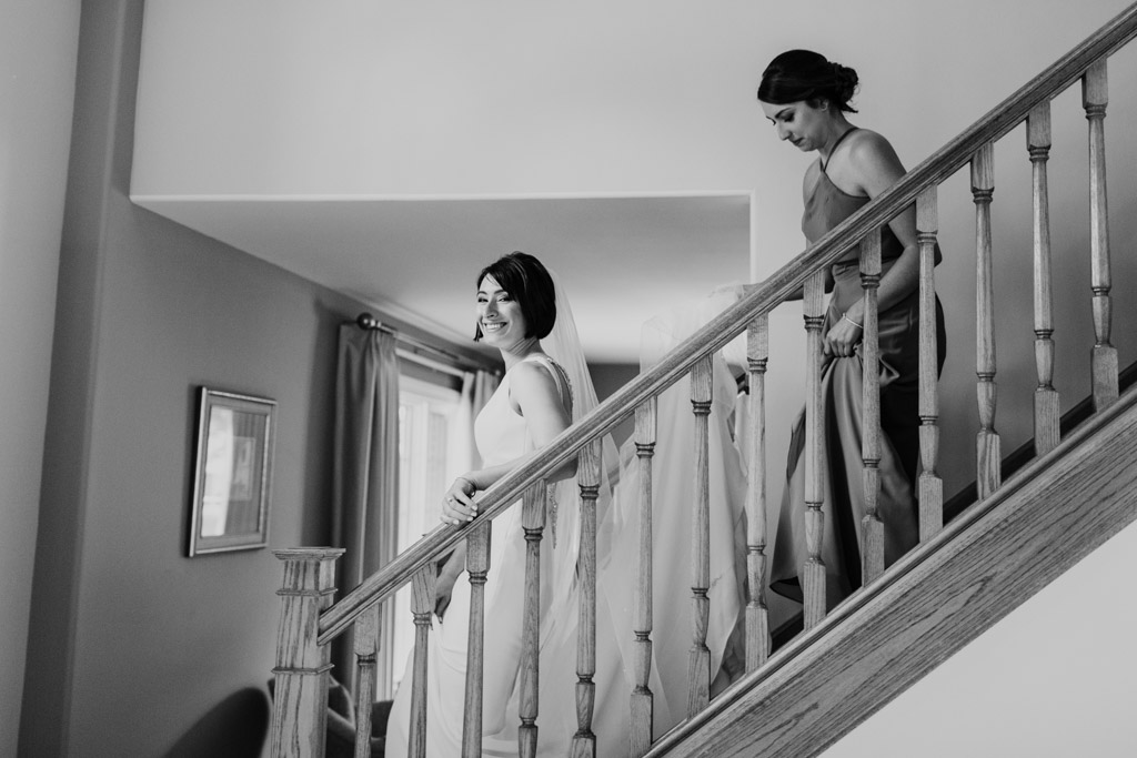 Bride and Maid of Honor coming down stairs before Chicago Greek Orthodox wedding ceremony