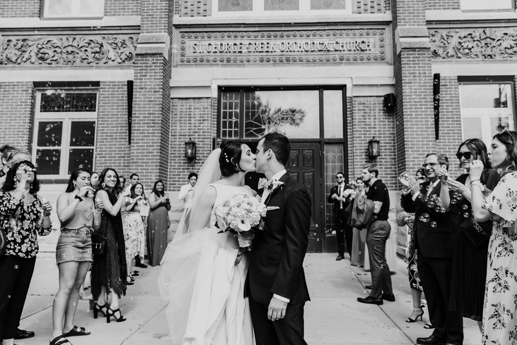 Bride and groom kiss during bubble exit after Chicago Greek Orthodox wedding ceremony