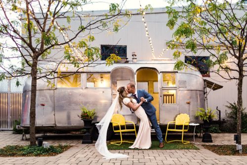 Warehouse 109 wedding photo of bride and groom kissing with Airstream in courtyard