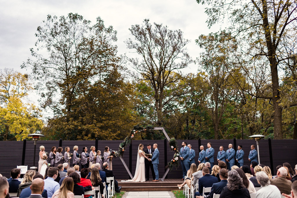 Fall Warehouse 109 wedding ceremony in outdoor garden with stylish wedding party