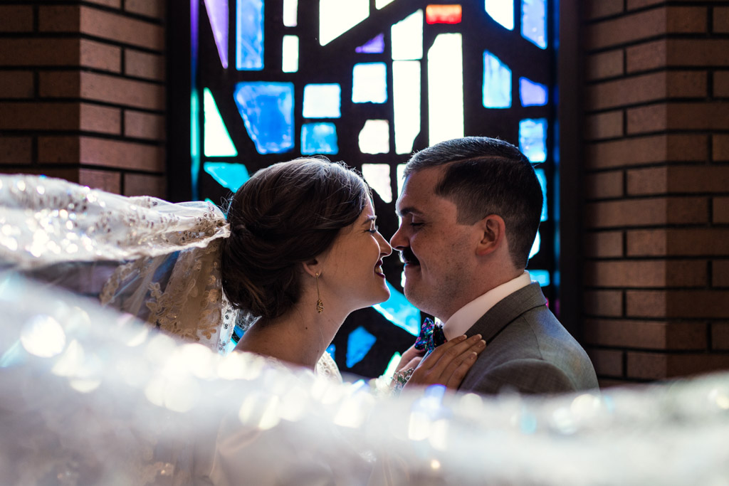 Romantic photo of bride and groom in church with stained glass