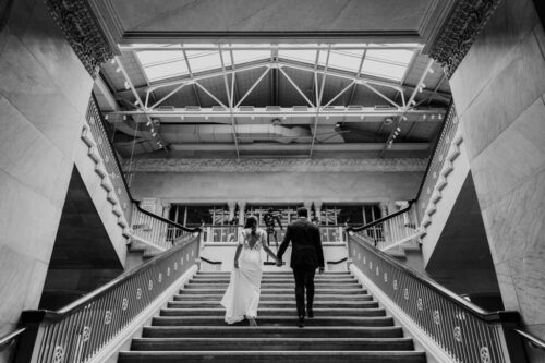 Bride and groom walk up grand staircase at their Art Institute of Chicago wedding