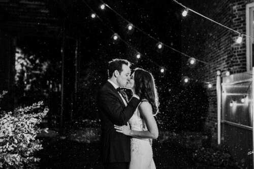 Romantic wedding photo of bride and groom kissing in rain at night at Firehouse Chicago
