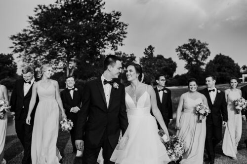 Bride and groom walk with wedding party at Sunset Ridge Country Club
