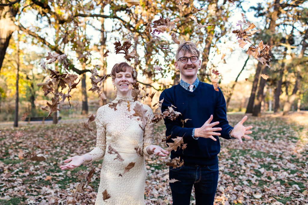 Happy bride and groom toss leaves at their Halloween wedding in Chicago