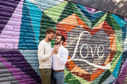 Happy couple with rainbow LOVE mural in Lincoln Park during their Chicago engagement session