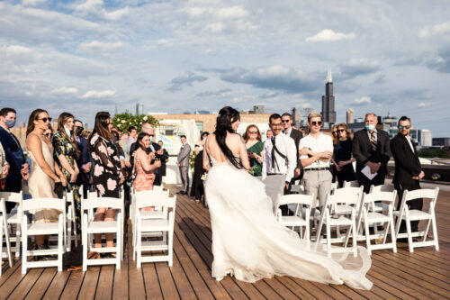 Guests stand as bride walks down the aisle at Ignite Glass Studios Chicago rooftop wedding ceremony