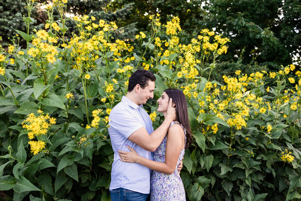 Romantic photo of engaged couple with sunflowers at Lincoln Park after surprise proposal at Alfred Caldwell Lily Pool