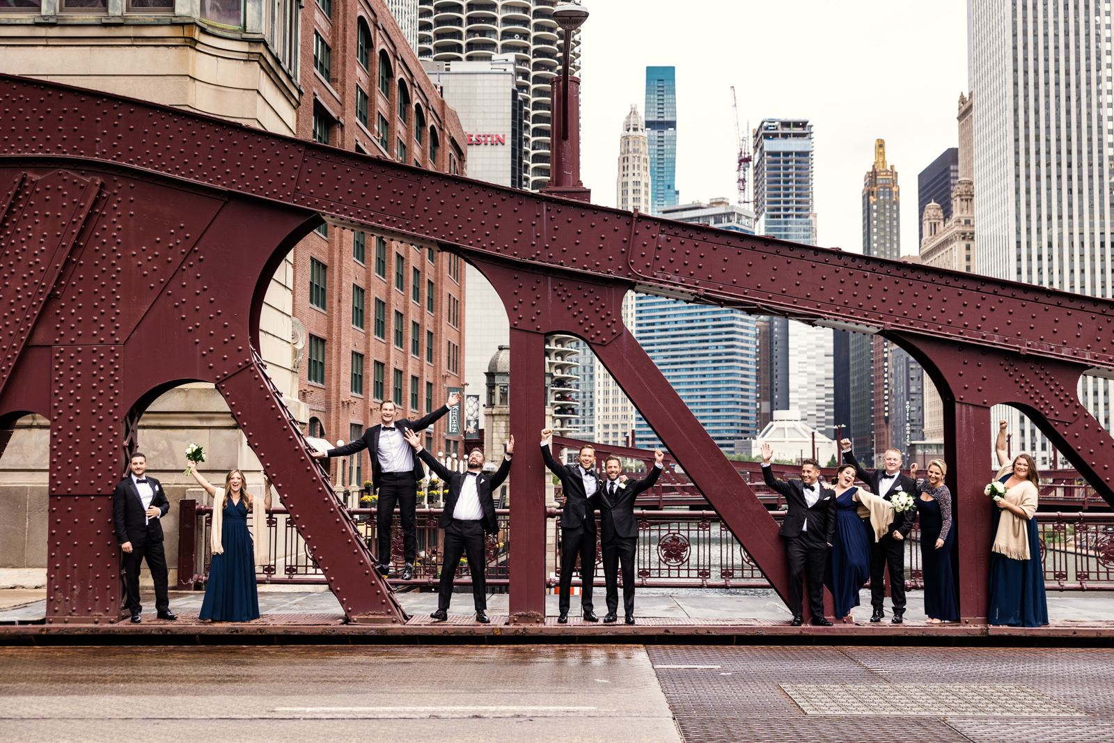 Two grooms and their wedding party celebrate on LaSalle Street Bridge by documentary wedding photographer Emma Mullins Photography