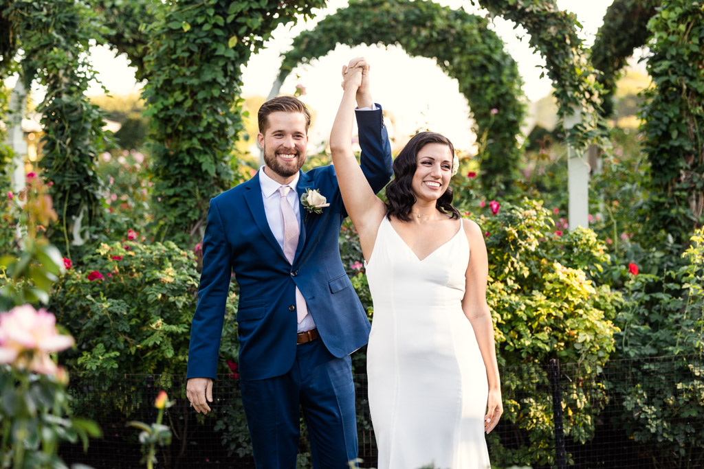 Just married bride and groom smile at their guests during Grant Park Rose Garden wedding ceremony