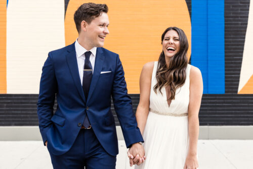 Candid photo of Chicago bride and groom walking with colorful mural in West Loop