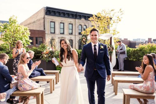 Just married bride and groom walk down aisle after Loft Lucia rooftop wedding ceremony