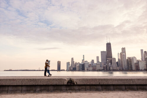 Romantic engagement photo with Chicago skyline and colorful sunset at North Avenue Beach