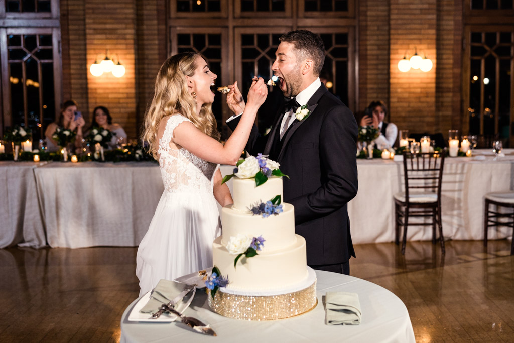 Bride and groom feed each other cake at their Cafe Brauer wedding reception in Chicago
