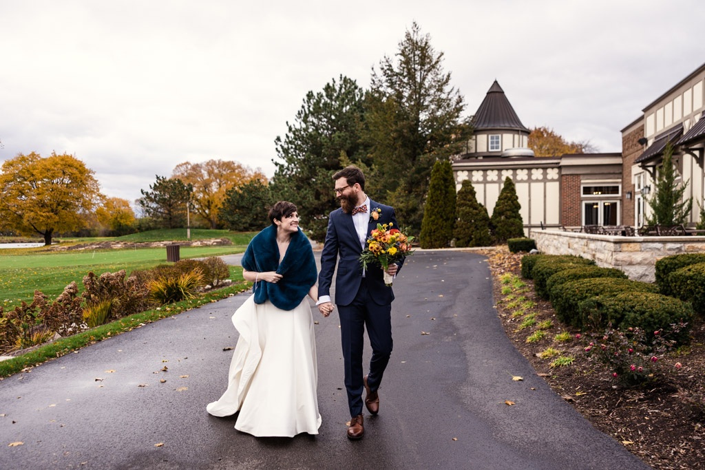 Candid photo of bride and groom walking outside at their fall Chevy Chase Country Club wedding