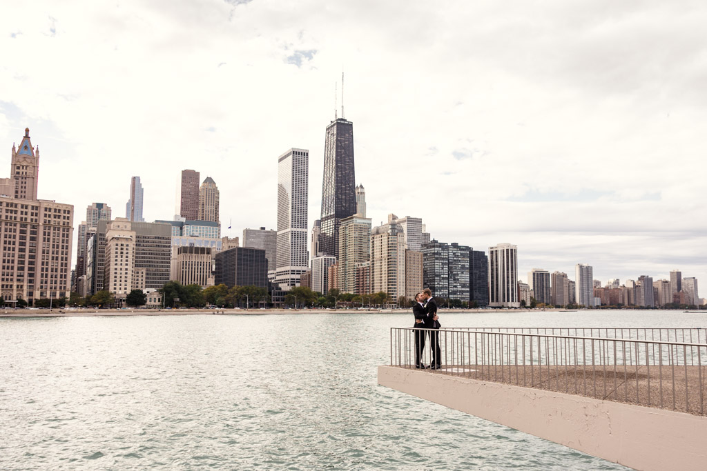 Grooms kiss at Olive Park with Chicago skyline overlooking Lake Michigan