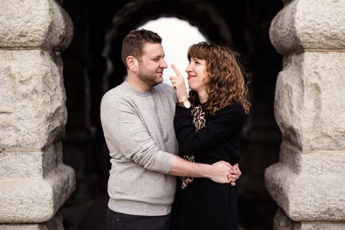 Candid photo of engaged couple standing in front of stone building in Lincoln Park